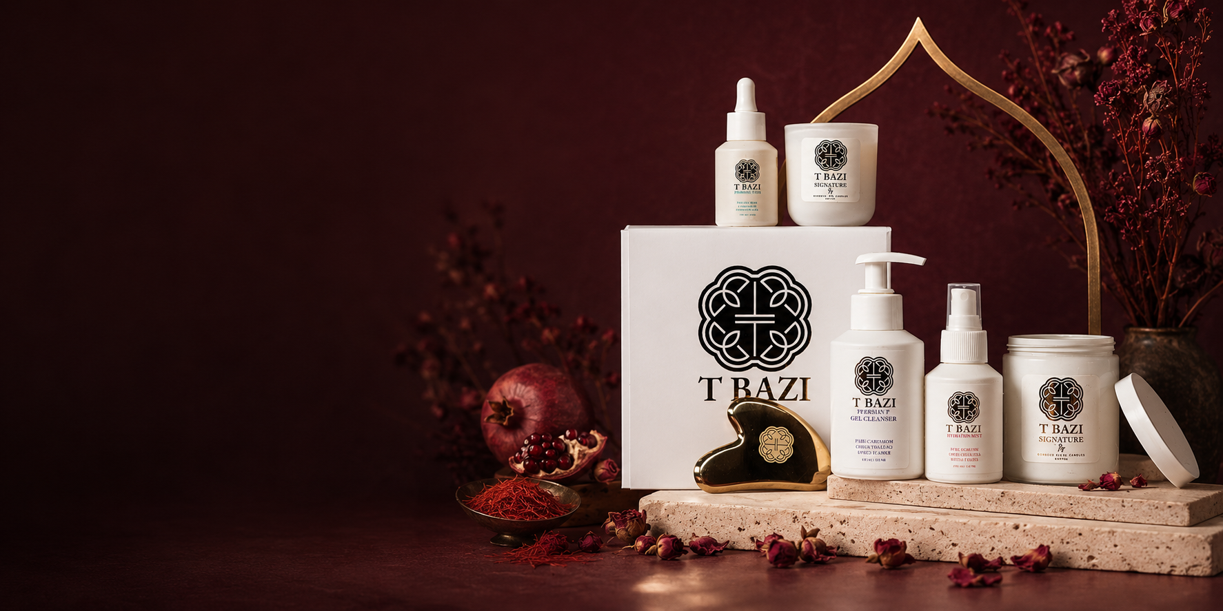 A T Bazi skincare set arranged on a stone slab against a dark maroon background, featuring white bottles, jars, and a box with black logos and text, styled with dried flowers, a pomegranate, and rose petals.